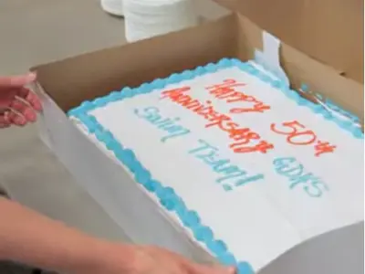 a close up of a cake that says "Happy 50th Anniversary GDHS Swim Team!"