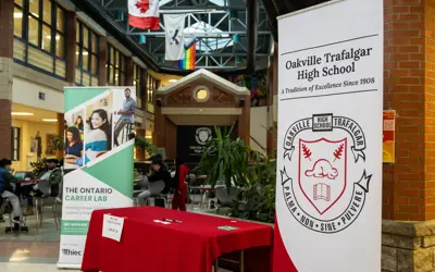 Banner for “The Ontario Career Lab” in a school lobby beside a red check-in table labeled “Welcome Career Coaches – Check-In.