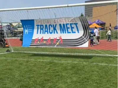 a soccer net on an outdoor field that has a large banner in it that reads "Special Athletics Track Meet"