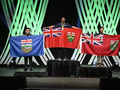 three students on a podium holding up provincial flags of Canada.