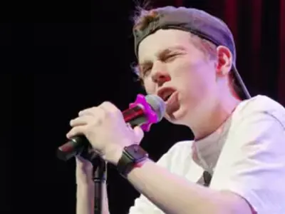 close up of a teenage boy singing into a microphone. 